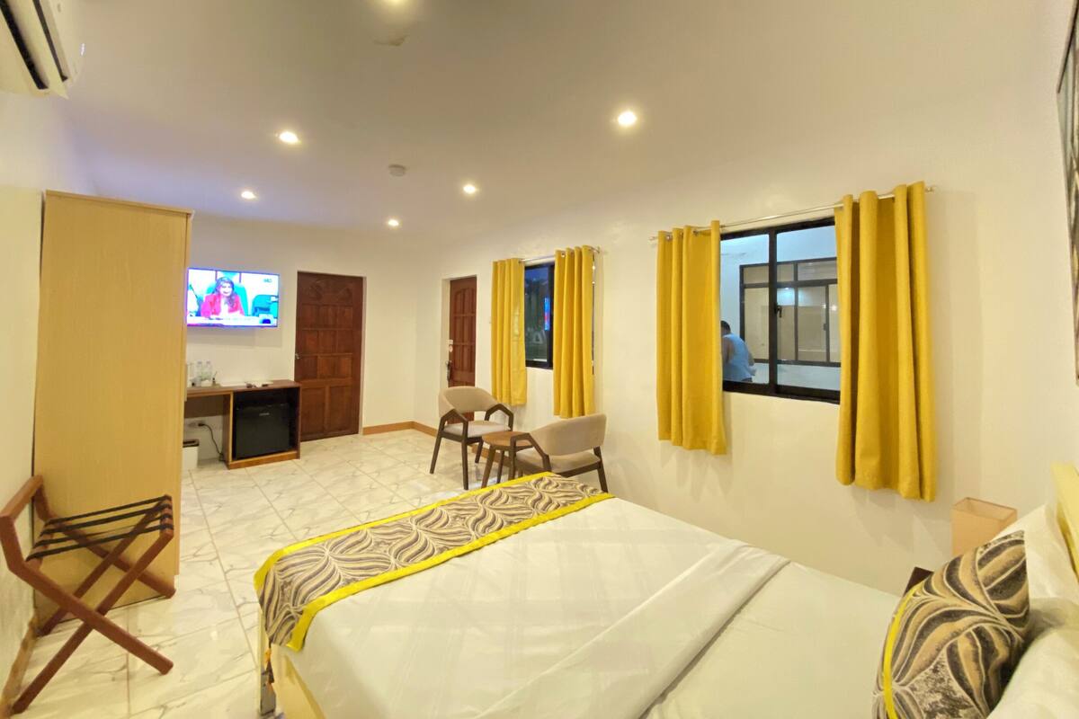 Una habitación de hotel con cama, escritorio, silla y televisión.