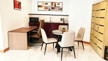 Cocina compacta con zona de comedor, que incluye una mesa redonda con sillas, un microondas y un mueble con cajones.