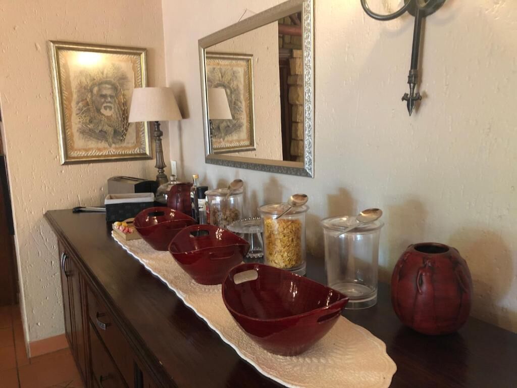 A kitchen counter with red bowls, jars, and a vase.