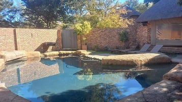 Una piscina al aire libre, sillones reclinables de piscina