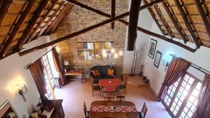A spacious dining area with a high ceiling and exposed brick walls. There is a central table with chairs and a red tablecloth. - Khaya Africa Guesthouse and Spa (Midrand)