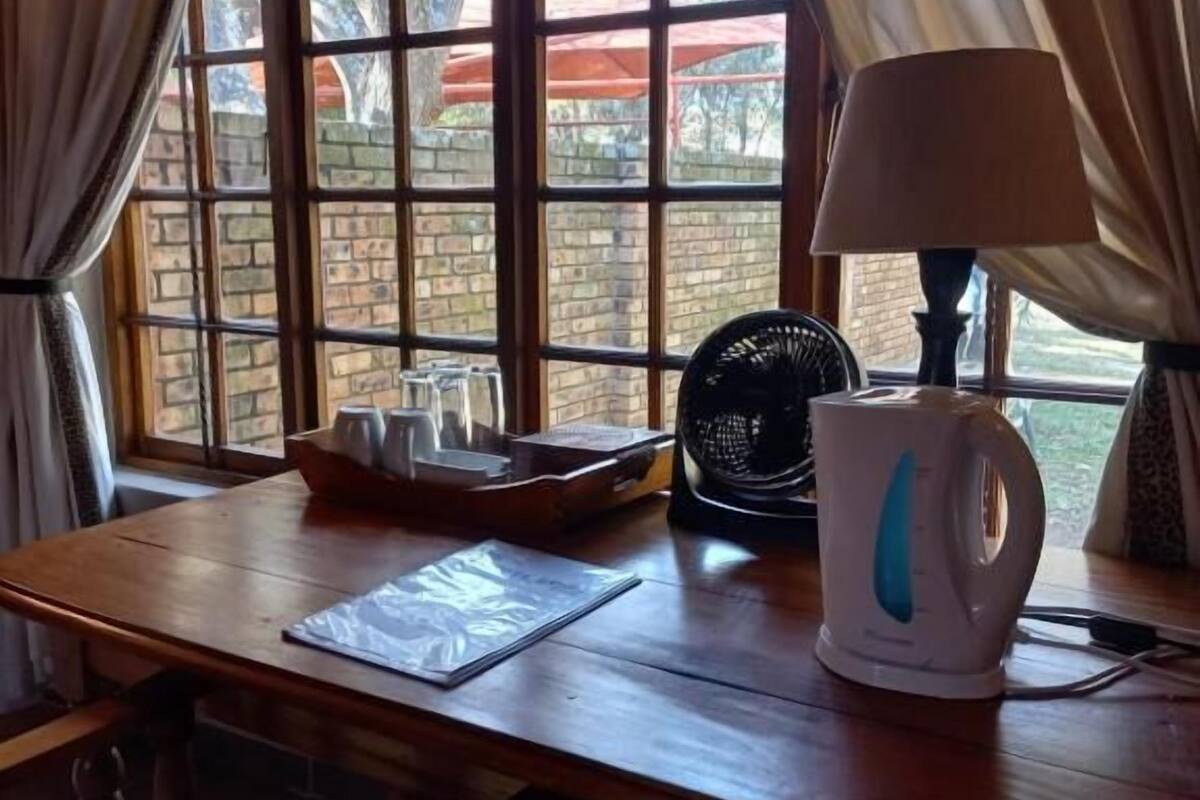 A wooden table with a kettle, a fan, and a lamp.