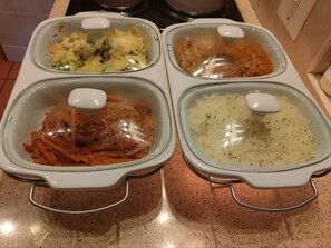 Quatre récipients en verre contenant de la nourriture, posés sur un plan de travail de cuisine.
