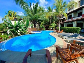 A swimming pool with lounge chairs and palm trees.