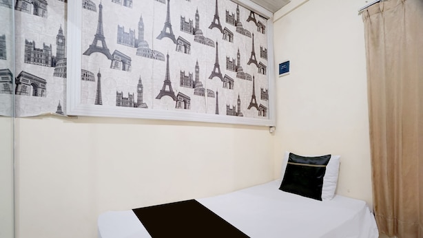 Ein Einzelbett mit einer schwarz-weißen Tagesdecke, einem Kissen und einer Wandstickerei mit Stadtansichten.