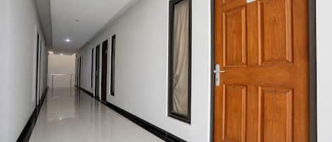 A corridor with doors on one side and a reflective floor.