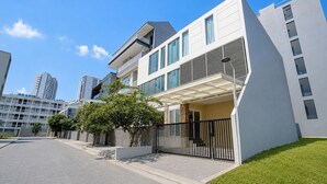 Un moderno edificio residencial de dos pisos con techo plano, ventanas grandes y un balcón.