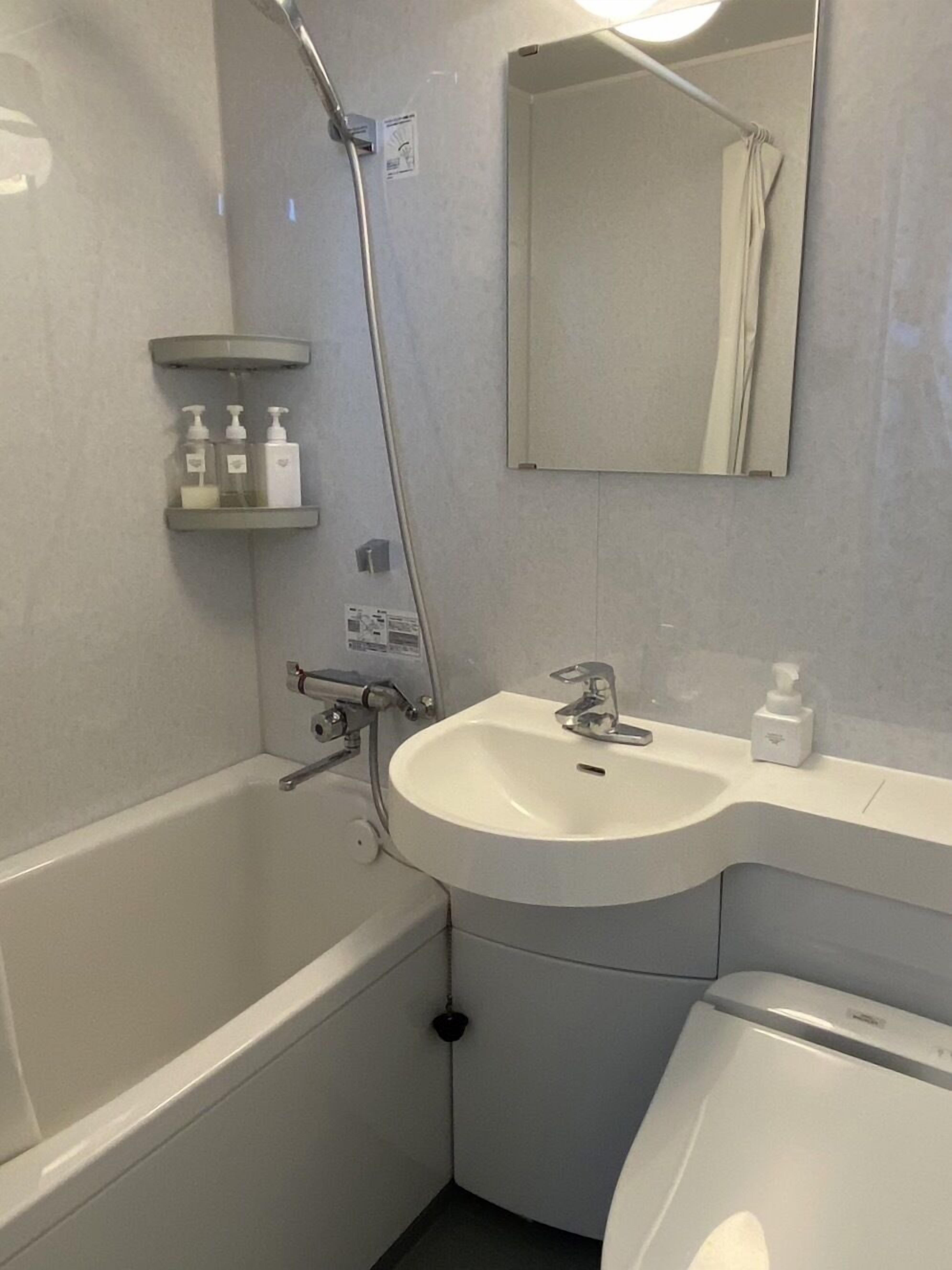 A bathroom with a bathtub, a sink, a mirror, and a shower.