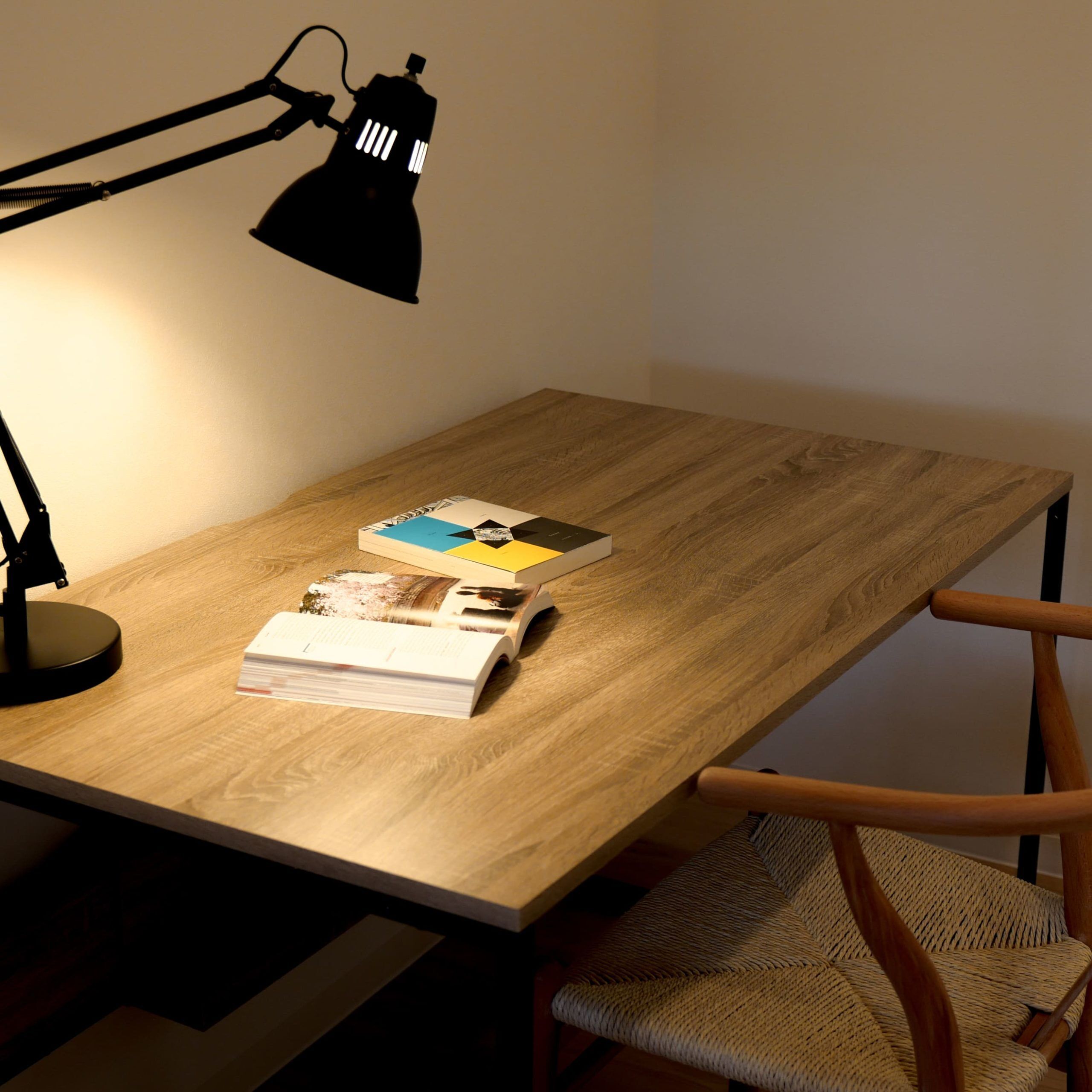 A wooden desk with a lamp, a chair, and some books.