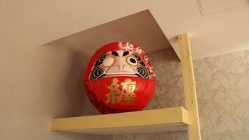 A red decorative object with gold writing on a shelf against a patterned wall.