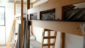 A bunk bed room with a ladder, a small desk, and a window. - Matoi Hostel & Bar (Takasaki)