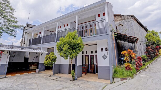 A two-story building with a balcony, a small garden area, and a paved entrance. - OYO 90405 Penginapan Sasti KuninganNearTaman Cirendang (Cilimus)
