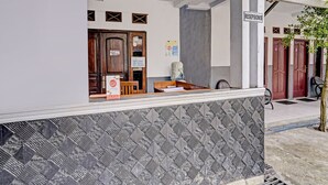 A reception area with a wooden desk, a signboard, and a reception desk. - OYO 90405 Penginapan Sasti KuninganNearTaman Cirendang (Cilimus)