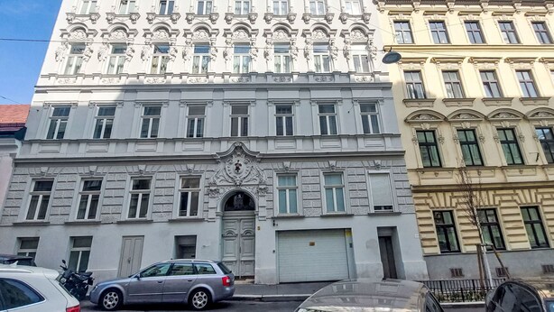 A multi-story building with classical architecture, featuring ornate details and a central entrance.