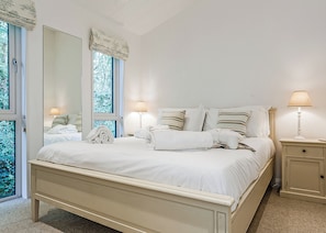 A bedroom with a bed, two bedside lamps, a nightstand, and a large mirror.