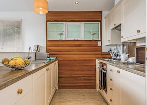 A kitchen with wooden paneling, a window with two birds, a fruit bowl, and a sink.