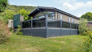 A modern house with a large glass extension, surrounded by a lush garden. - Harbour Premier Lodge (Mullion Cove, Helston)