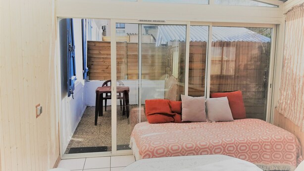 Un dormitorio con cama, una silla y una puerta corrediza de vidrio que da a un patio.