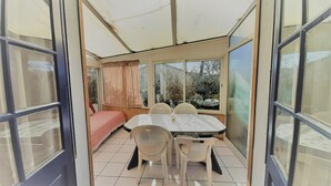 Una habitación con una mesa de comedor, sillas, una cama y ventanas amplias.