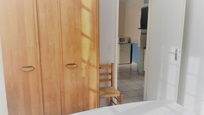 Un dormitorio con un armario de madera, una pequeña silla de madera y una cama.