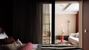 Una habitación de hotel moderna con una cama grande, un sofá, una mesa de comedor y vistas al exterior.