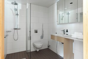 A modern bathroom with a glass shower enclosure, a toilet, and a sink with a mirror above.