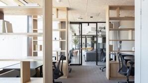 Un espacio de oficina con escritorios abiertos, estanterías y modernas sillas de oficina.