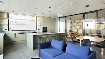 Una cocina moderna con una isla central, taburetes de bar y un comedor con mesa redonda y sillas.