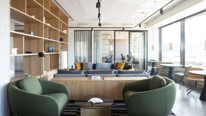 Un salón moderno con un conjunto de sofás, sillones verdes, una mesa de centro y una estantería.