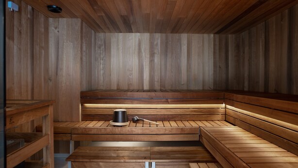 Una sauna con bancos de madera y un asiento con un balde y un cepillo.