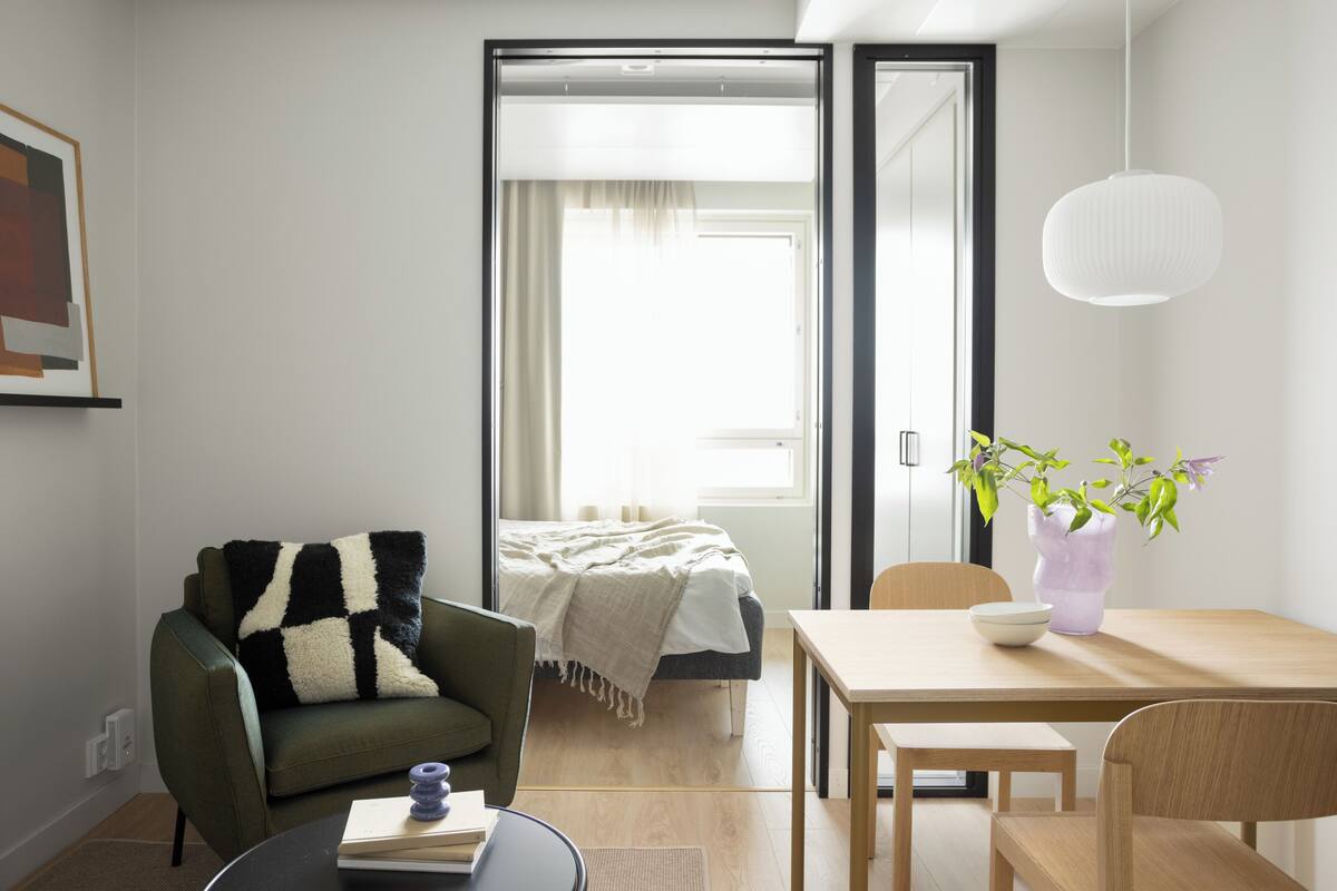 A modern living room with a sofa, a dining table, and a bed.