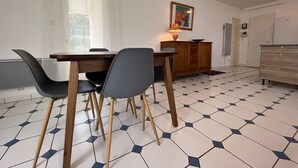 Ein Essbereich mit einem Holztisch, Stühlen, einem Schrank und einem Fliesenboden.