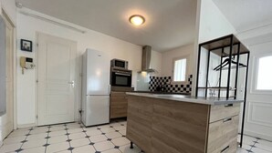 Eine moderne Küche mit Kochinsel, weißen Schränken, einer Mikrowelle und einem Kühlschrank.