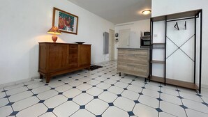 Eine Küche mit Mikrowelle, Backofen und Schränken. Der Boden ist mit sechseckigen Fliesen belegt und es gibt einen Holzkasten mit einer Lampe.