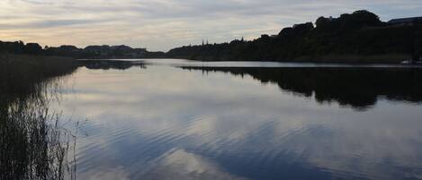 A calm lake with a clear reflection of the sky and surrounding landscape.