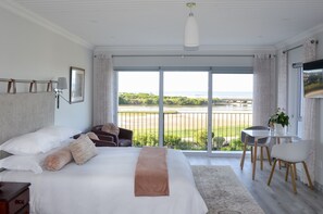 Un dormitorio con una cama grande, un escritorio y vistas al océano.