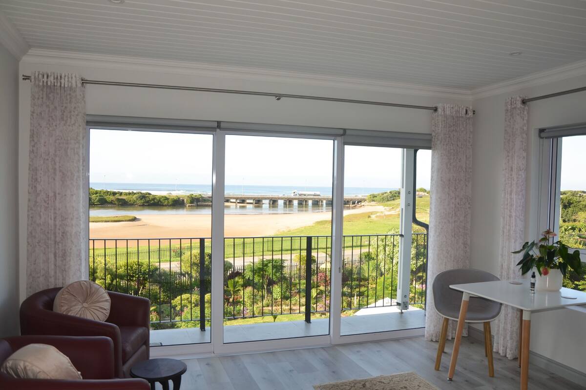 A spacious balcony with a view of a golf course and the ocean.