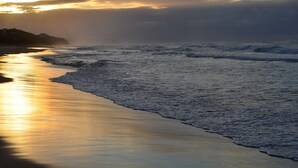 A beach with waves and a sunset. - Serenity Ocean Lodge (Wilderness)