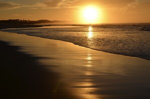 Una playa al atardecer, con mar tranquilo y cielo despejado.