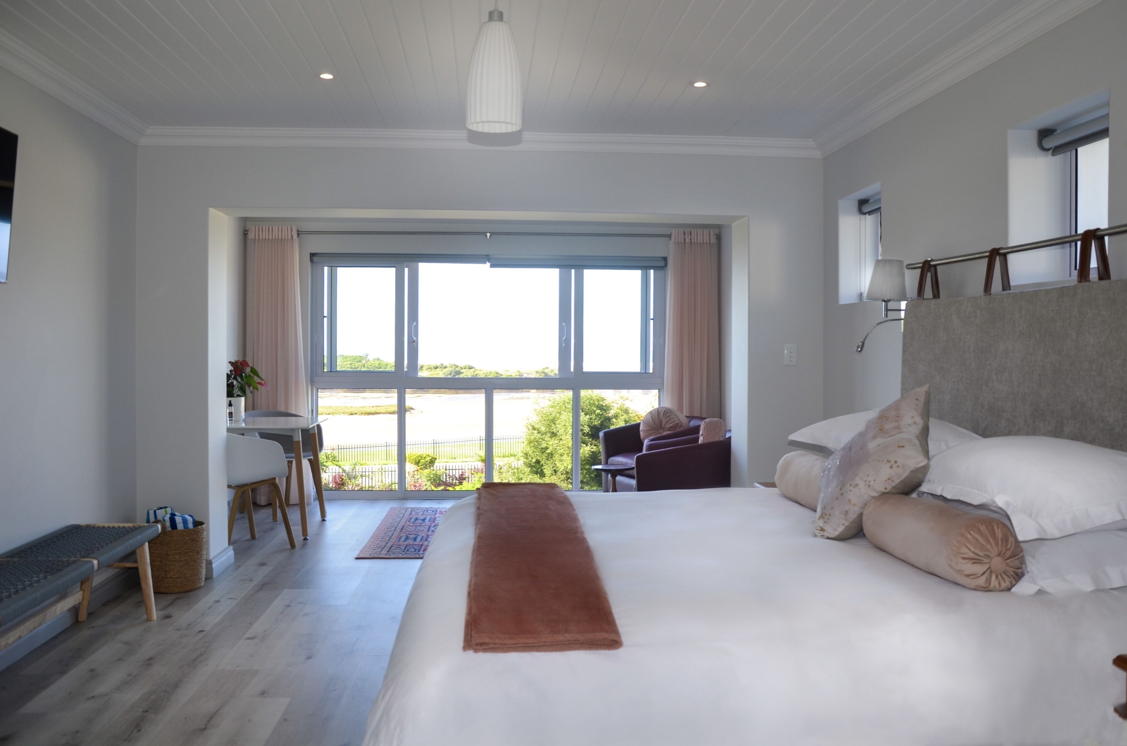 Un dormitorio con una cama grande, un escritorio y vistas al exterior.