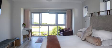 Un dormitorio con una cama grande, un escritorio y vistas al exterior.