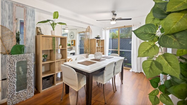 A dining area with a wooden table, white chairs, and a ceiling fan.