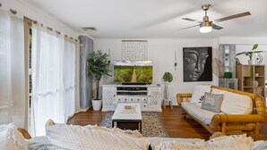 A living room with a sofa, a coffee table, a TV, and a ceiling fan.