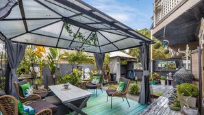 A covered patio area with wicker furniture, a table, and potted plants.