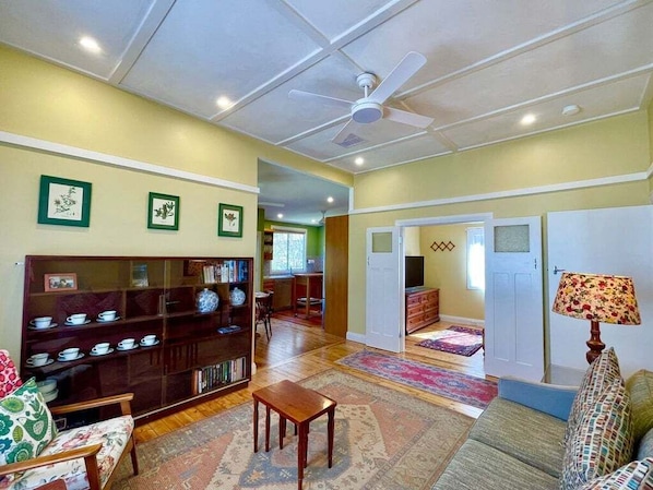 A living room with a bookshelf, a sofa, a coffee table, and a ceiling fan.