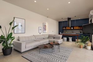 A modern living room with a sectional sofa, a coffee table, and a kitchen area with a bar.