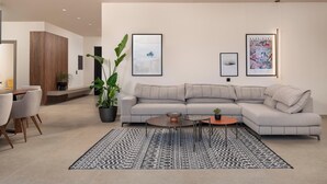 A modern living room with a sectional sofa, a coffee table, a dining area with chairs, and a large potted plant. - Mirena Luxury Living - Casa Di Ria (Αφάντου)