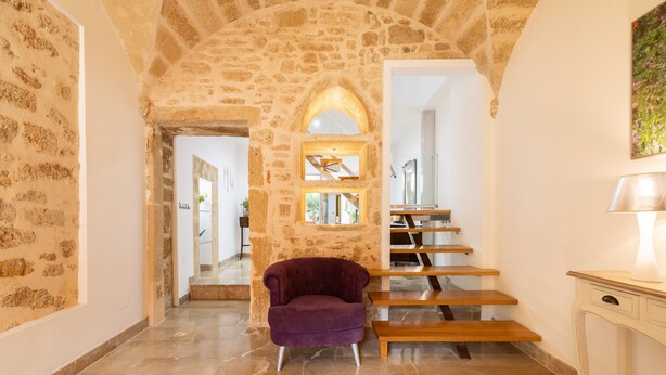 A stone-walled hallway with a purple chair and a staircase. - Ca Se Predine by Rentallorca (Alcúdia)