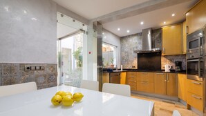 A modern kitchen with a white dining table, a stove, an oven, and a microwave. - Ca Se Predine by Rentallorca (Alcúdia)