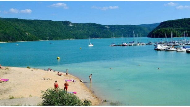 Une plage avec une eau turquoise et limpide, des bateaux et des gens.